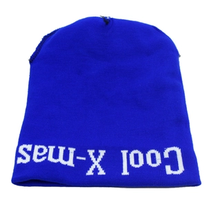 Detail of blue knitted Christmas hat with Cool X-mas text and white fluffy pom pom