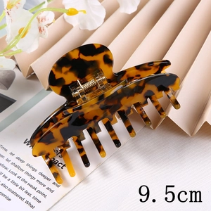 Detail showing a 9.5cm tortoiseshell acetate hair claw clip on a decorative background