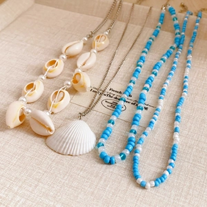 Detail of a 4-piece layered necklace set with cowrie shells, pearls, and blue beads