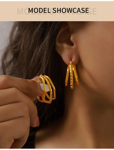 Close-up of triple-layered intertwined gold titanium earrings worn by a female model