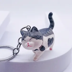 Cute cartoon cat keychain with gray stripes and heart pattern on a white platform