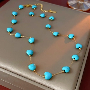 Detail shot of heart-shaped blue turquoise beads on a golden chain necklace