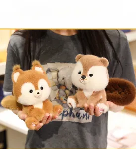 Close-up of hand holding two small plush squirrels with fluffy tails in brown tones