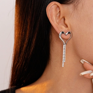 Close-up of heart-shaped silver earrings with sparkling rhinestone tassels on model
