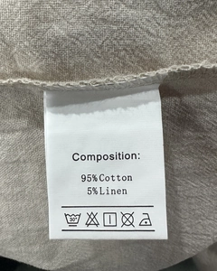 Detail of fabric care label showing 95% cotton and 5% linen blend for casual trousers