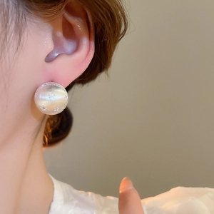 Close-up of 18k gold plated round pearl earring with star pattern on female model