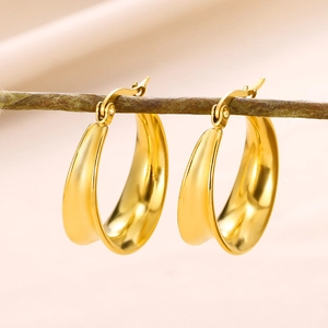 Close-up of gold geometric hollow hoop earrings hanging on a natural wooden branch
