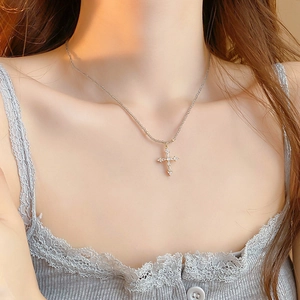 Gros plan détaillé du pendentif croix argenté orné de pierres de zircon brillantes