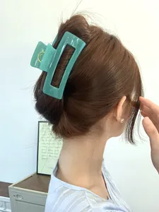 Mint green large rectangular hair claw clip shown styling a half-up bun for women