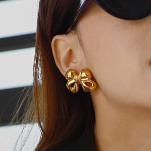Nahaufnahme eleganter goldener Schleifenohrringe mit poliertem Finish am Model
