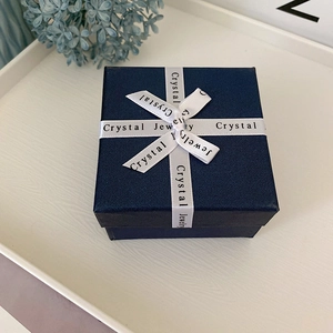 Detail of dark blue jewelry box with textured surface and white ribbon bow tie