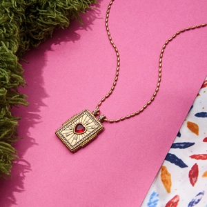 Macro detail of a vintage 18K gold stainless steel pendant with red heart zircon crystal