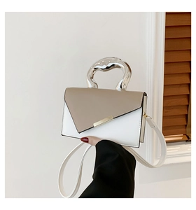 Detail of crossbody bag featuring an irregular silver metal handle and contrast color flap