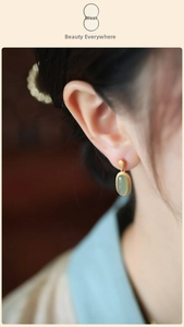 Detail of vintage matte gold earring with oval jade gemstone on female model ear