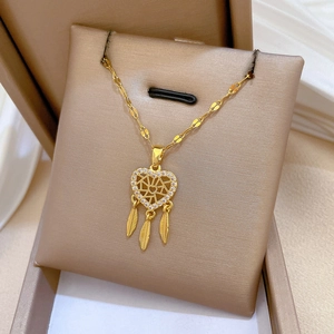 Dettaglio della collana acchiappasogni dorata a cuore con piume su cuscino per gioielli