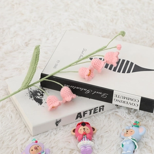 Close-up of handmade crochet pink lily of the valley flower resting on a book