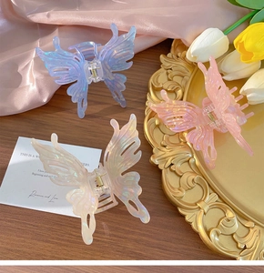 Three acrylic butterfly hair claws in blue pink and white on a vintage tray with tulips