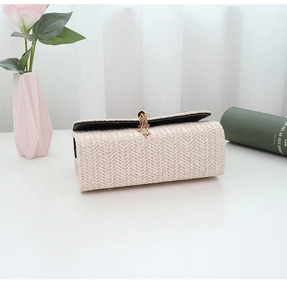 Detail of off-white woven straw bag with elegant gold tassels on white background