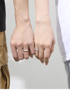 Close-up of S925 silver couple rings with minimalist diamond and wing design on hands