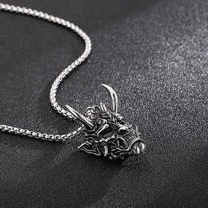 Macro shot of silver demon mask pendant with sharp horns and fangs on a metal chain
