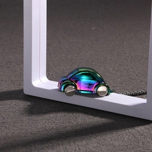 Détail d'un pendentif voiture 3D en métal arc-en-ciel irisé sur une surface texturée