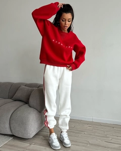 Close-up of red crewneck sweatshirt with embroidery and white striped joggers
