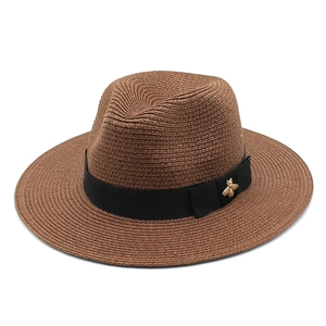 Close-up of brown straw fedora featuring a black ribbon and gold bee accent
