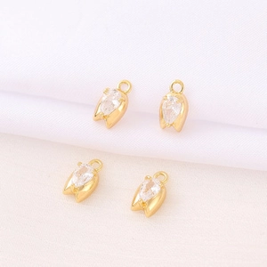 Detailed view of four tulip-shaped gold-plated pendants with teardrop zircon crystals