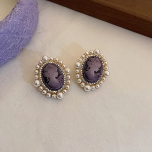 Detail view of vintage oval earring with purple cameo portrait and pearl trim
