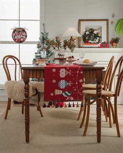 Close-up of red knitted Christmas table runner with festive bells and colorful pompom tassels
