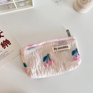 Detail showing pink floral embossed texture and cherry pattern on a mini pouch bag