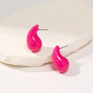 Detail of rose red teardrop earrings with a glossy finish on white stone background