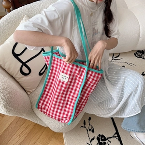 Detail of red and white checkered canvas tote bag with contrast piping and logo tag