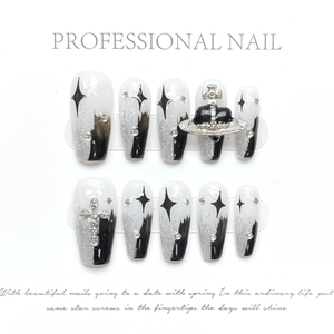 Macro detail of star pattern and silver planet charm on monochrome tweed press-on nails