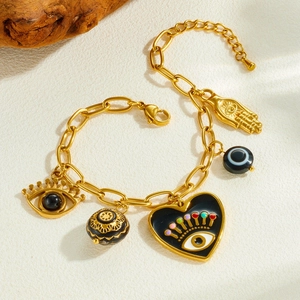 Bracelet à breloques doré avec cœur œil et main de Hamsa sur surface texturée
