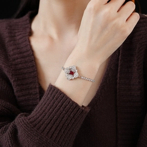 Close-up of silver flower bracelet with a red gemstone and clear crystals on a wrist