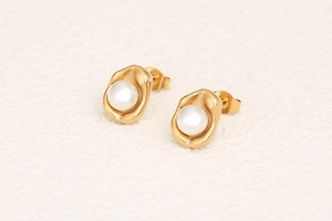 Detailed macro view of elegant gold pea-shaped earrings with round white pearls