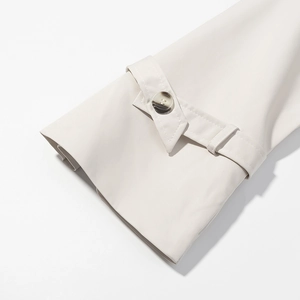 Detailed macro view of the cream-white trench coat cuff with strap and button detail