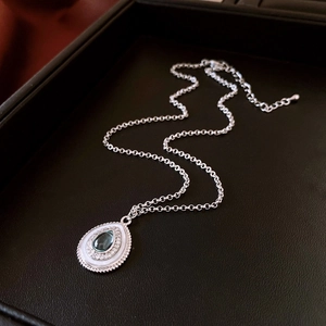 Detailed macro view of pear-shaped green zircon pendant with silver beaded edges