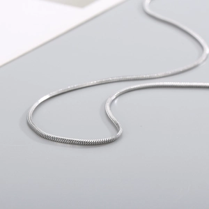 Macro detail of a polished silver snake chain necklace with smooth metallic texture