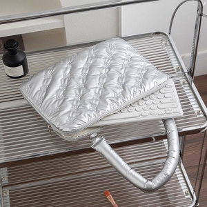 Detail of silver quilted laptop bag with bow pattern and thick padded handles