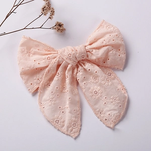 Pink embroidered lace bow hair clip for girls on a clean minimalist background