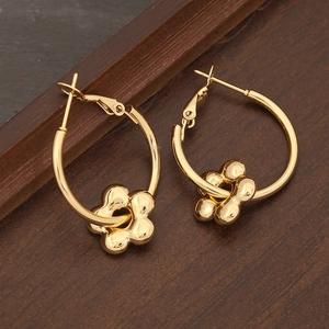 Elegante goldene Blumenohrringe mit fünfblättrigem Anhänger auf dunkler Holzmaserung