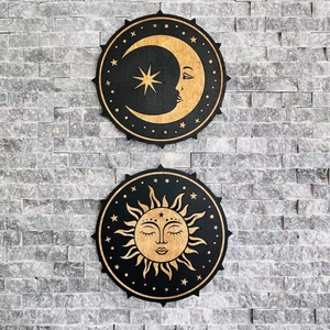 Detail of two wooden sun and moon wall art plaques on a grey stone brick surface
