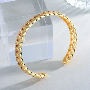 Macro shot of 18k gold plated open cuff bracelet with red and white zircons