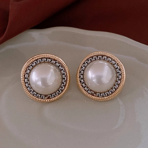 Macro view of vintage round pearl studs with gold rope and silver chain metal borders