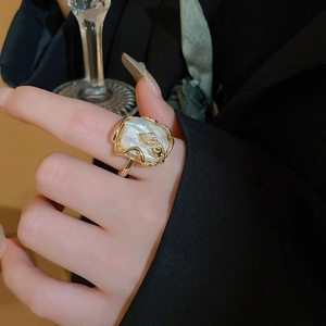 Détail d'une bague en nacre baroque avec motif feuille dorée et cristaux brillants