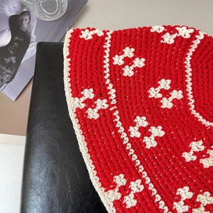 Detail of red and white handmade crochet knit bucket hat showing intricate floral pattern