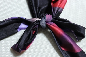 Detail of a silk texture digital print scarf with vibrant gradient colors and knot technique