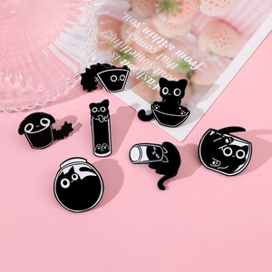 Set of seven cartoon black cat enamel pins in various funny liquid shapes on pink desk